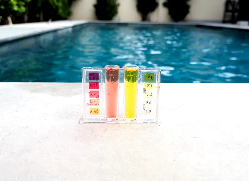 A professional swimming pool water testing kit showing chlorine and pH levels next to a clear blue villa pool in Dubai.