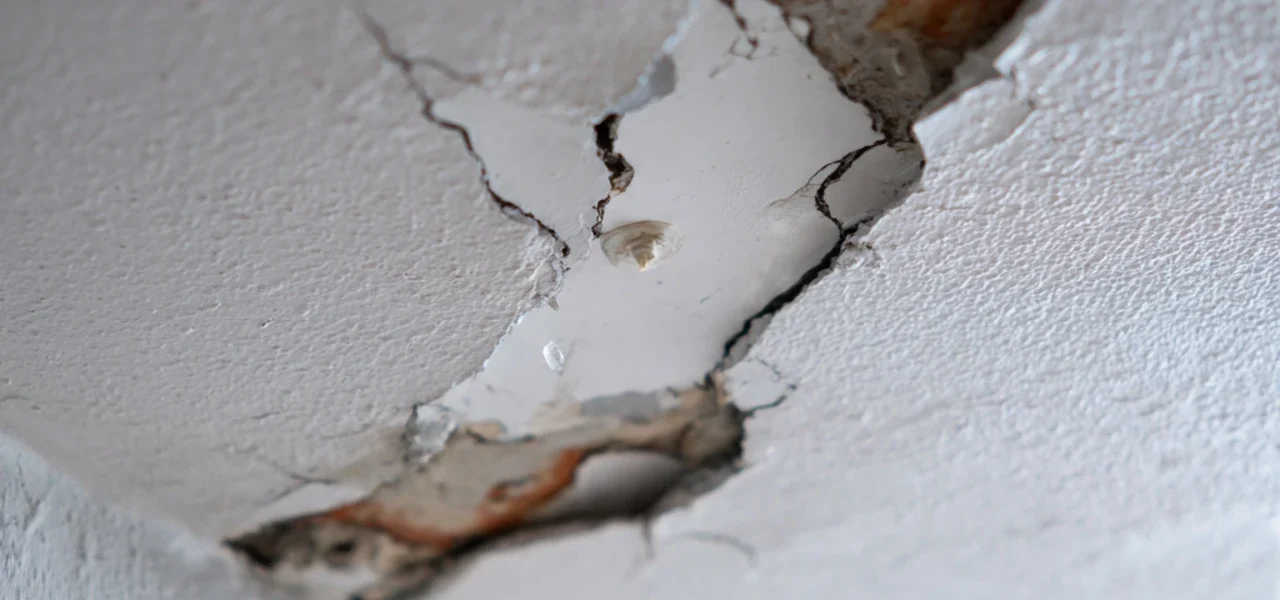 Close-up of severe water leakage damage in a gypsum ceiling of a Dubai villa, showing structural cracks and moisture buildup requiring professional plumbing service.