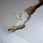 Close-up of severe water leakage damage in a gypsum ceiling of a Dubai villa, showing structural cracks and moisture buildup requiring professional plumbing service.